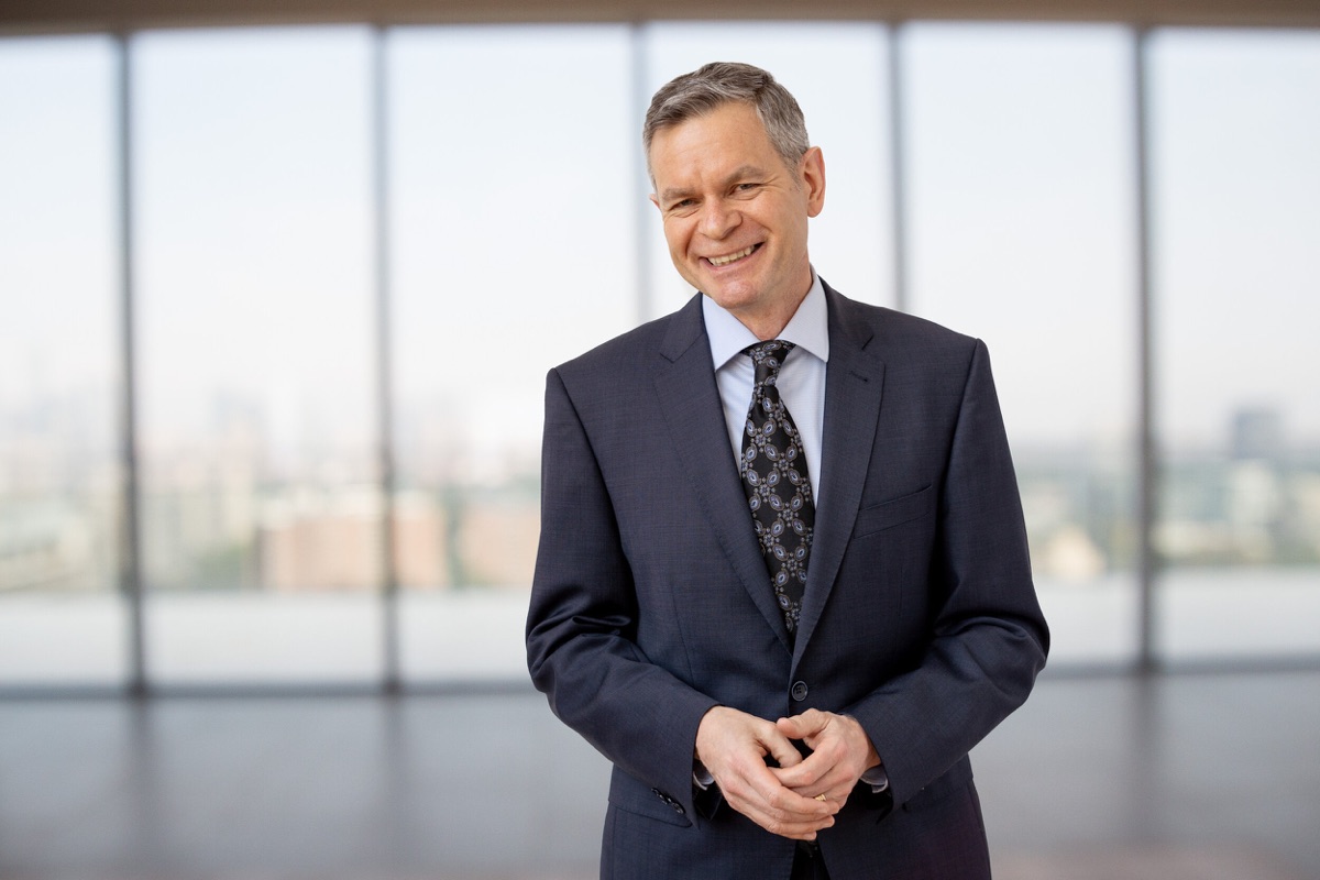 Graham Binks smiling in a navy suit in front of a bright office window